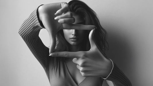 a black and white photo of a woman making a wall art frame with her fingers and hands. Modern wall art canvas painting online India. Free delivery. Ready-to-hang premium quality wall art painting decor. Modern art prints and framed posters.